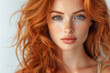 © TATIANA - Front view portrait of young woman with long curly red hair on a white background.