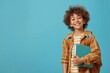 © VISUAL BACKGROUND - A smiling boy holding a book against a blue background.