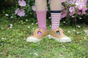 Kid wears different pair of socks. Child foots in mismatched socks standing outdoor.  Down syndrome awareness concept, odd socks day, anti-bullying week.