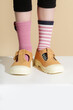 © triocean - Kid wears different pair of socks. Child foots in mismatched socks, studio photography. Down syndrome awareness concept, odd socks day, anti-bullying week.