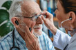 © Neha - Doctor fitting a senior’s ear with a hearing aid