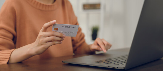 Close-up of hand holding credit card and type on laptop keyboard with online payment for shopping.