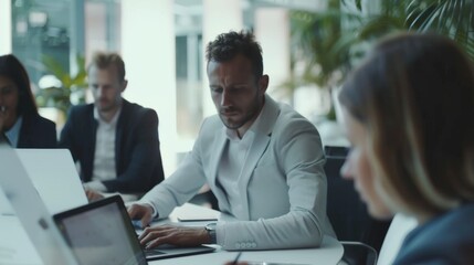 Poster - In a modern office, a diverse team of managers utilizes laptops and tablets to discuss business projects. Young, motivated and experienced employees brainstorm together in a conference room.
