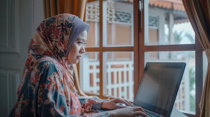 Poster - The image shows a young female Muslim student at home using a laptop. She is attending remote education during the day and writing an essay assignment. Arc shot taken from outside the window shows