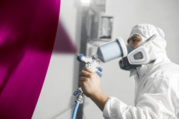 Wall Mural - Car painter spraying paint with spray gun on part of car in paint chamber, complex painting, heavy color selection. Restoration of automobile after the accident.