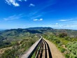 © Wirestock - A narrow trail in the Marin headlands with a wooden rail in the foreground and blue sky above it