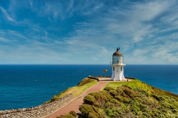 Wall Mural - Majestic lighthouse stands at the top of a lush green hill in New Zealand, Cape Reinga