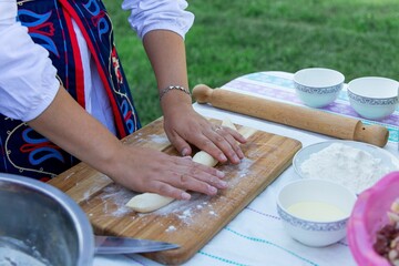 Female wearing a traditional Kyrgyz outfit is cooking manty, a type of Central Asian food.