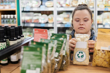 Over shelf portrait of adult woman with disability arranging displays while working in supermarket copy space