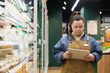 © Mediaphotos - Waist up portrait of young woman with disability working in supermarket and using digital tablet for stock review copy space