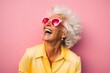 © Markus Schröder - Portrait of a content woman in her 80s laughing in front of solid pastel color wall