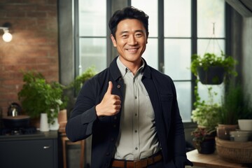 Wall Mural - Portrait of a glad asian man in his 40s showing a thumb up on scandinavian-style interior background