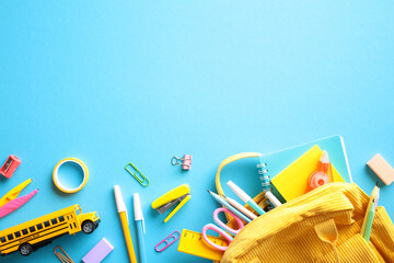 Wall Mural - Vibrant School Essentials. A lively and colorful composition featuring a variety of school supplies, including a yellow bus toy, an assortment of pencils, notebooks, and a backpack, on a blue backdrop