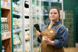 © Mediaphotos - Waist up portrait of confident young woman with Down syndrome working in supermarket and looking at camera enjoying independent living copy space