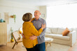 © Jordi Salas - Senior couple dancing together in their living room, sharing a moment of joy and affection. Senior couple dancing and holding hands, enjoying each other's company in a cozy environment.