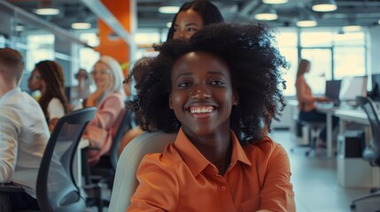 Poster - Employee pushes his beautiful female colleague on a chair between rows of desks with diverse business people working on desktop computers in modern office space.