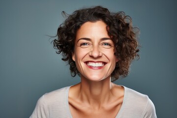 Wall Mural - Portrait of a grinning woman in her 40s smiling at the camera on blank studio backdrop