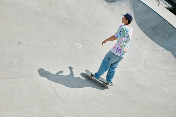 Wall Mural - A young skater boy performing a daring skateboard descent down the ramp at an outdoor skate park on a sunny summer day.