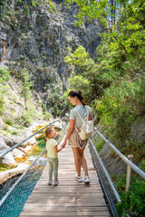 Wall Mural - Mother with little girl hiking in Sapadere canyon with wooden paths and cascades of waterfalls in the Taurus mountains, Turkey. Eco tourism concept