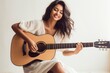 © Markus Schröder - Portrait of a satisfied indian woman in her 20s playing the guitar isolated on light wood minimalistic setup