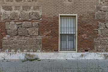 Wall Mural - Brick wall with a low window with black painted metal grille