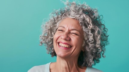 Joyful older female with curly grey hair, contemporary style, solid teal background, bright lighting, casual outfit