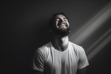 Wall Mural - Portrait of a glad man in his 30s laughing while standing against bare monochromatic room