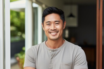 Wall Mural - Portrait of a joyful asian man in his 30s smiling at the camera while standing against stylized simple home office background