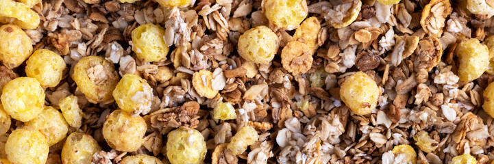 Organic roasted crispy granola cereal with oatmeal and flaxseed flakes and crunchy corn balls and rings banner. Top view muesli background texture panoramic web header. Wide screen wallpaper