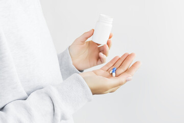 Wall Mural - woman holding two blue and white medicine capsules on her palm and empty white plastic jar