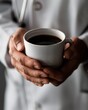 © Xyeppup - Close-up of a doctor's hands holding a warm cup of coffee, taking a brief respite in a quiet hospital corner, reflecting on the day's duties.
