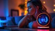 © K-MookPan - A woman relaxes on a couch at night, listening to music on a smart speaker.  The speaker glows with colorful lights, casting a warm ambiance.