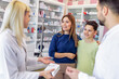 © Mediteraneo - Cheerful pharmacist chemist man giving vitamins to young mom with son in the modern pharmacy.