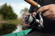 © smiltena - Freshwater fishing in summer. Spinning reel on a spinning rod in the hands of a fisherman.