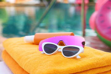 Wall Mural - Beach towels, sunglasses and sunscreen on sunbed near outdoor swimming pool, closeup. Luxury resort