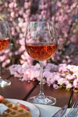 Canvas Print - Glasses of rose wine on table in spring garden