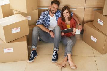 Poster - Smile, tablet and couple with boxes in house for moving in or out on floor for social media with humor. Portrait, internet and shopping for new furniture or selling online for fresh start in Canada.