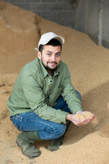 Wall Mural - Male farmer holding a handful of soybean husks in an animal feed warehouse