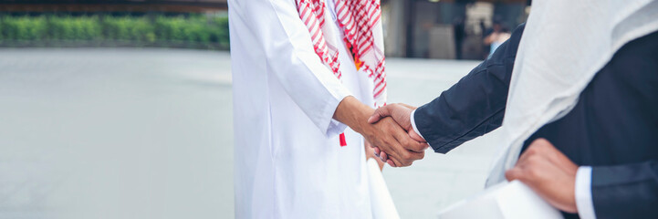 Banner Arab Businessman shaking hands together. Teamwork business partner wear Muslim dress Shake Hands partnership. Banner Success UAE diversity people trust commitment handshake with copy space