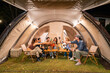 © Kawee - Group of diverse friend having outdoors camping party together in tent.