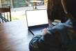 © Farknot Architect - Mockup image of a woman working on laptop computer with blank white desktop screen in cafe