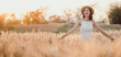 © Satori Studio - A woman is standing in a field of tall golden wheat, wearing a straw hat and smiling. Concept of happiness and freedom, as the woman is enjoying the beauty of nature and the simple pleasures of life