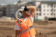© Volodymyr - Builder with hardhat helmet on construction site. Construction engineer worker in builder uniform near construction building. Portrait of builder in a construction site build new house.