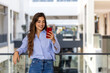 © Graphicroyalty - Happy confident young business woman using cell mobile phone . Smiling lady professional holding cellphone standing in the modern building looking away working outside office.