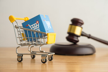 Trolley, online shopping boxes and hammer judge on wooden background. Consumer rights and responsibilities to safety, customer protection in online shopping e-commerce, commercial law concept.