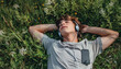 © Mirador - Young man lying in the grass with headphones, enjoying music on a summer day. The serene and carefree moment epitomizes relaxation and the joy of music