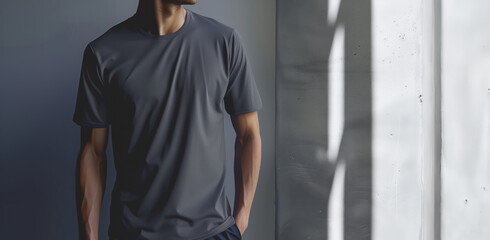 Wall Mural - Man Standing in Sunlit Room Wearing a Grey T-Shirt with Hands in Pockets, Mockup