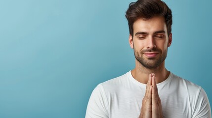 Wall Mural -  A man, eyes closed, stands before a blue backdrop, hands folded in front