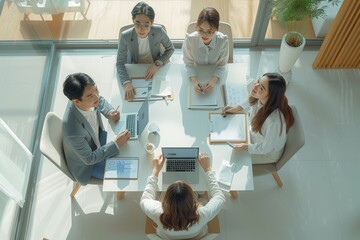 Poster - Top view angle of modern minimalist a group asian staff wears a causal modern cloth with modern hairstyle, is happily brainstorm in modern office with laptop and document on a table. Generative AI.