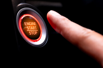 The driver's hand is pressing the car start button. Concept of transportation and technology	
